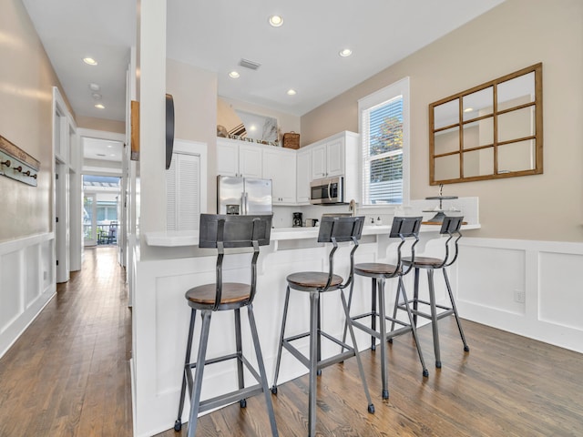 kitchen with white cabinetry, stainless steel appliances, a breakfast bar, and kitchen peninsula