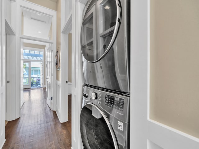 laundry room featuring stacked washer / drying machine and dark wood-type flooring