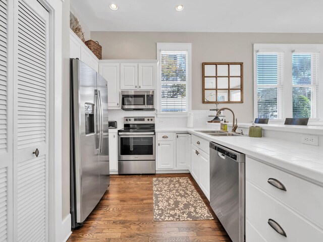 kitchen with dark wood-type flooring, appliances with stainless steel finishes, and white cabinetry