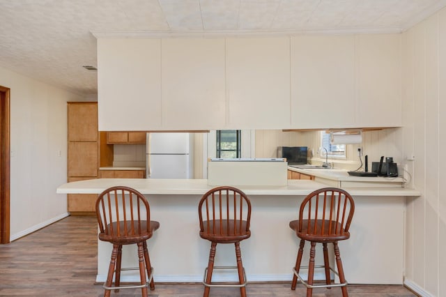 kitchen with kitchen peninsula, a healthy amount of sunlight, white refrigerator, and wood-type flooring