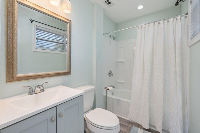 full bathroom with hardwood / wood-style flooring, vanity, shower / bath combo with shower curtain, and toilet