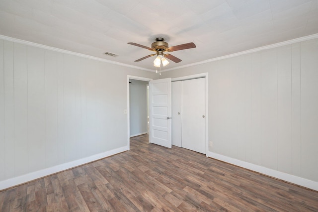 unfurnished bedroom featuring ornamental molding, wooden walls, ceiling fan, and dark hardwood / wood-style floors