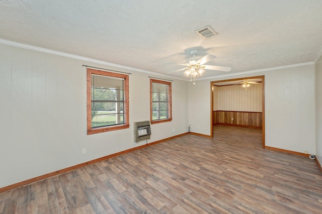 unfurnished room with wood-type flooring, heating unit, ornamental molding, and a textured ceiling