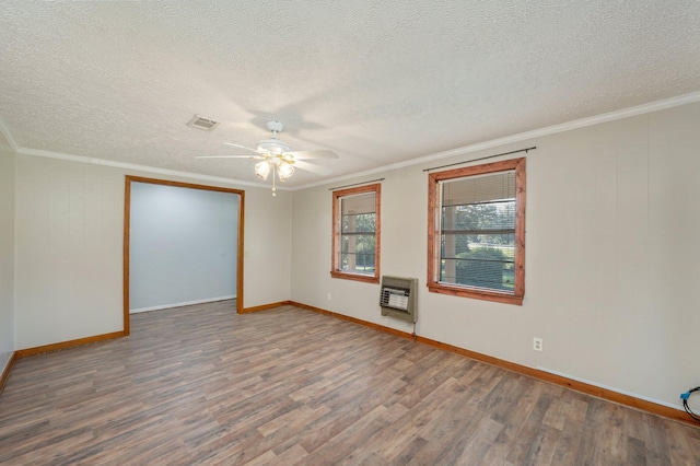 spare room featuring ceiling fan, hardwood / wood-style floors, heating unit, crown molding, and a textured ceiling