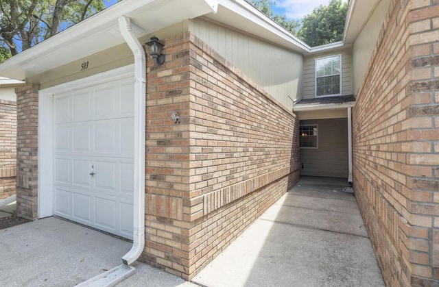 view of exterior entry featuring brick siding and an attached garage