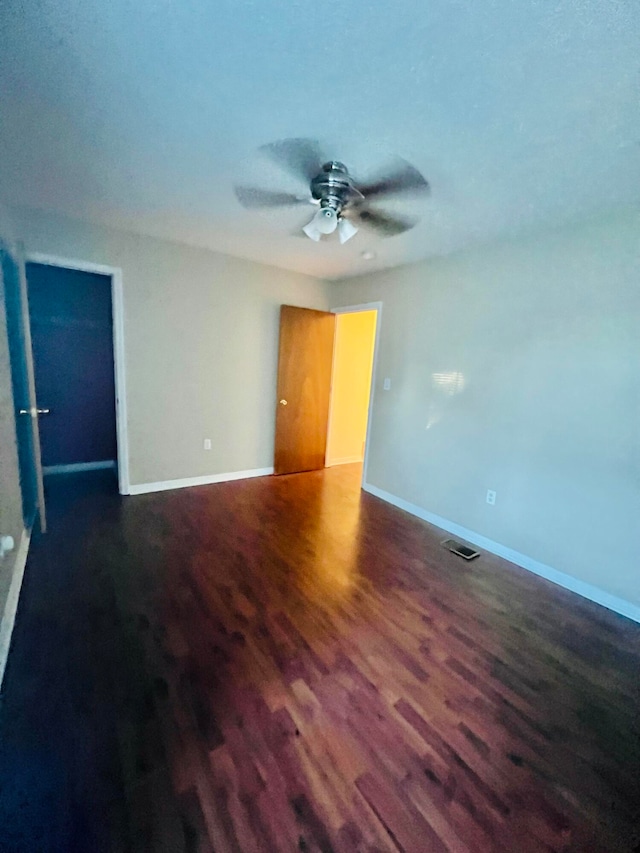 spare room featuring dark wood-type flooring and ceiling fan