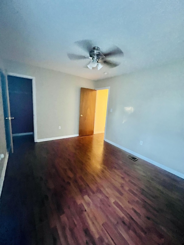 empty room with a ceiling fan, baseboards, visible vents, and wood finished floors