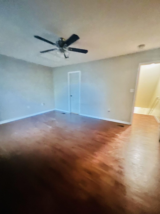 unfurnished room featuring a ceiling fan, baseboards, and wood finished floors