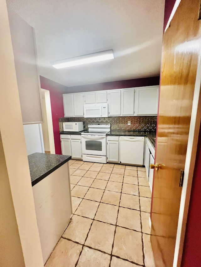kitchen with dark countertops, white appliances, white cabinetry, light tile patterned floors, and tasteful backsplash