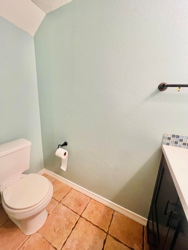 bathroom featuring vanity, lofted ceiling, toilet, and tile patterned flooring