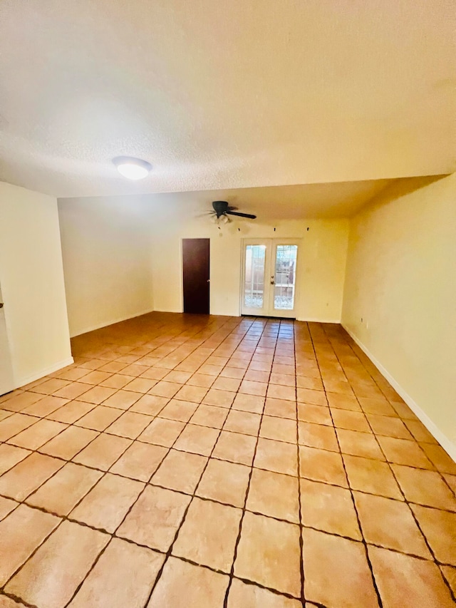 tiled empty room featuring french doors, a textured ceiling, and ceiling fan