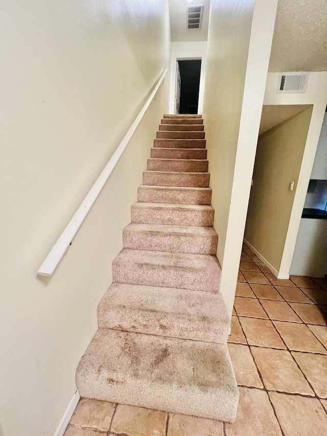staircase featuring tile patterned floors, baseboards, and visible vents