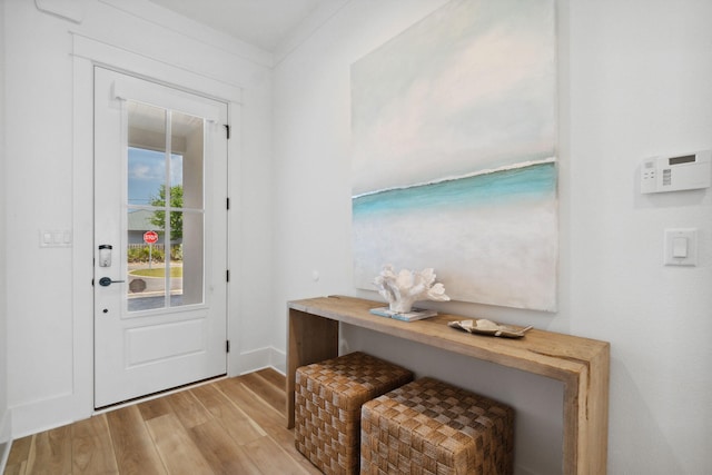 doorway to outside featuring light hardwood / wood-style flooring and crown molding