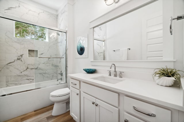 full bathroom with wood-type flooring, shower / bath combination with glass door, vanity, and toilet