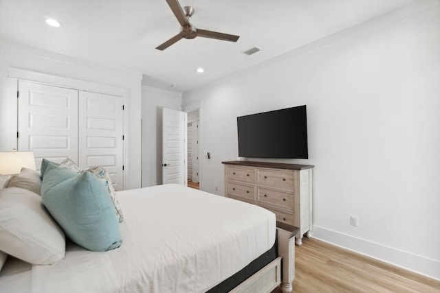 bedroom featuring a closet, crown molding, light hardwood / wood-style flooring, and ceiling fan