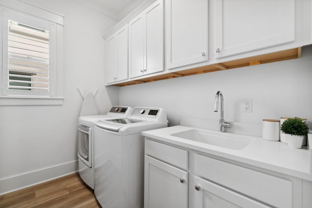 laundry room with independent washer and dryer, cabinets, hardwood / wood-style flooring, and sink