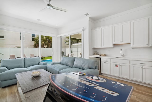 living room with ornamental molding, ceiling fan, sink, and light hardwood / wood-style floors