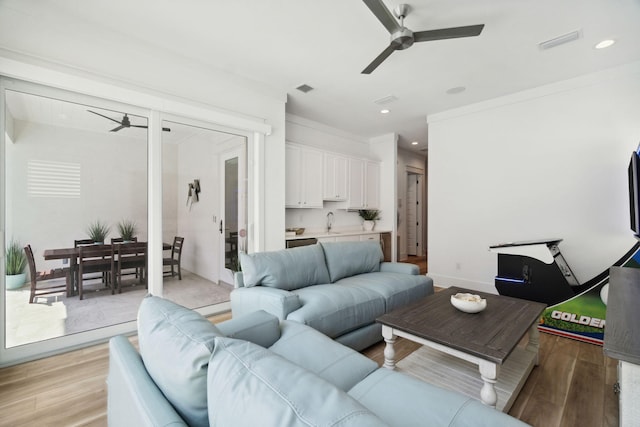 living room featuring a ceiling fan, visible vents, and light wood-style flooring