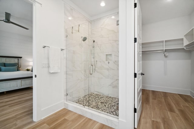 bathroom with a stall shower, ceiling fan, connected bathroom, wood finished floors, and baseboards