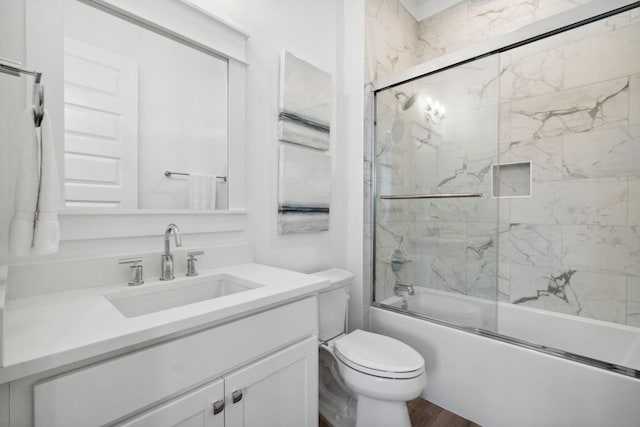 full bathroom with wood finished floors, vanity, toilet, and bath / shower combo with glass door