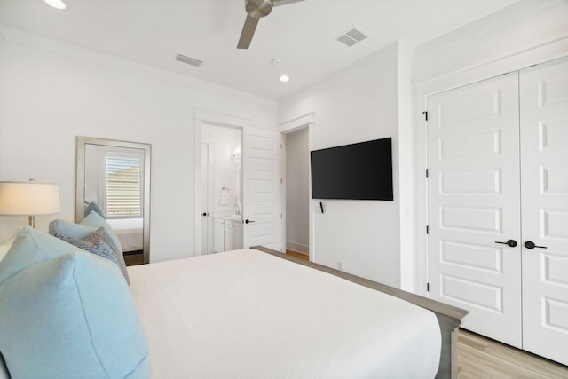 bedroom featuring light wood-style floors, ceiling fan, visible vents, and a closet