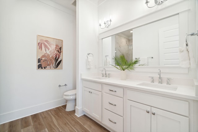 bathroom with toilet, double vanity, a sink, and wood finished floors