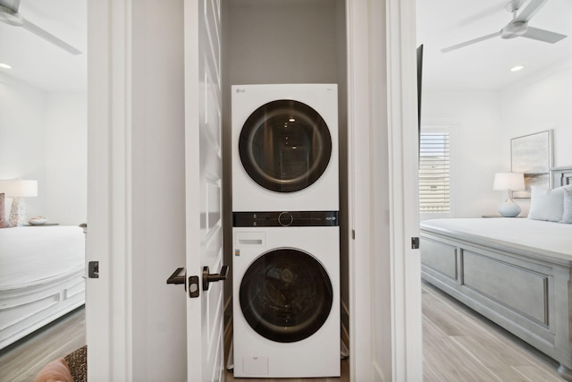 laundry area with stacked washing maching and dryer and light hardwood / wood-style flooring