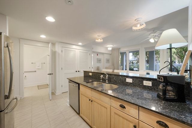 kitchen with light tile patterned flooring, ceiling fan, dark stone countertops, sink, and appliances with stainless steel finishes