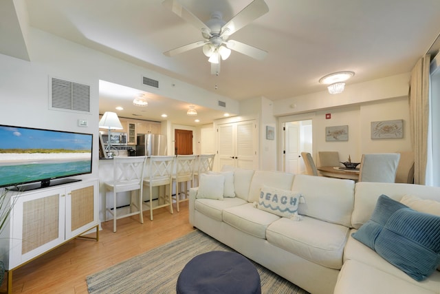 living room with ceiling fan and light hardwood / wood-style flooring