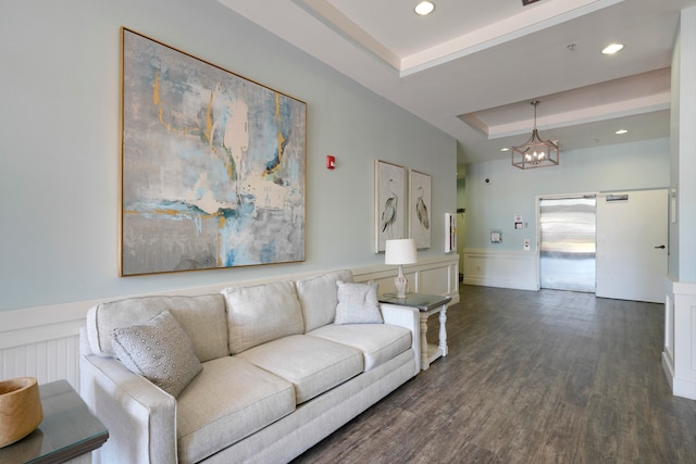 living room featuring a notable chandelier, a tray ceiling, and dark hardwood / wood-style flooring