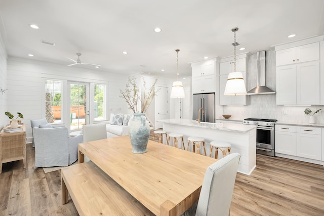 dining room featuring ceiling fan, wooden walls, and light hardwood / wood-style floors