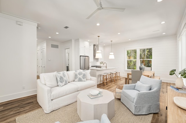 living room with crown molding, ceiling fan, and light hardwood / wood-style flooring