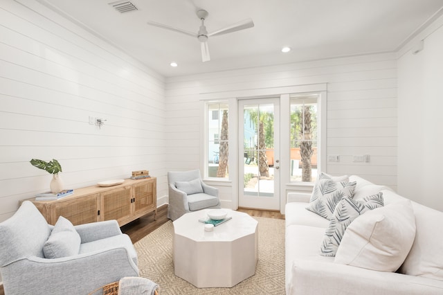 living room featuring ceiling fan, wood walls, and light hardwood / wood-style flooring