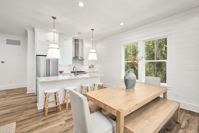 dining space with wooden walls, crown molding, and light hardwood / wood-style floors