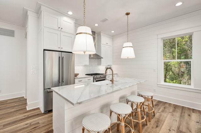 kitchen with pendant lighting, white cabinets, a center island with sink, and high quality appliances