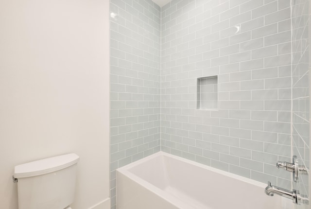 bathroom with toilet and tiled shower / bath