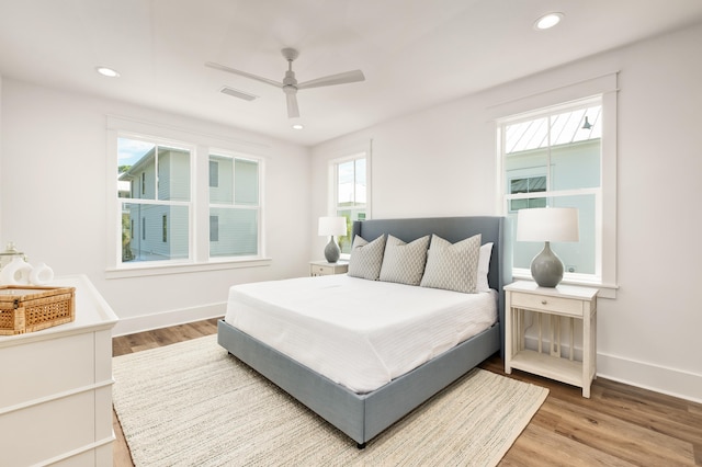 bedroom with ceiling fan, hardwood / wood-style flooring, and multiple windows