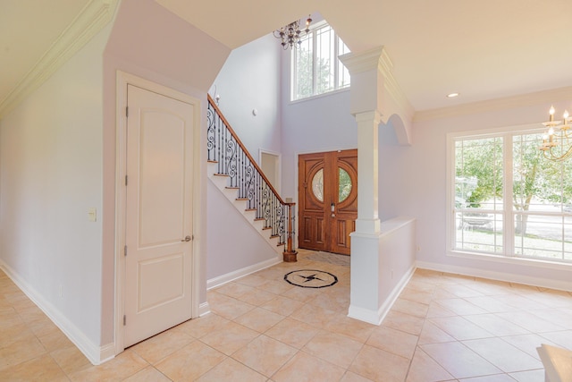 tiled foyer with plenty of natural light, decorative columns, and an inviting chandelier