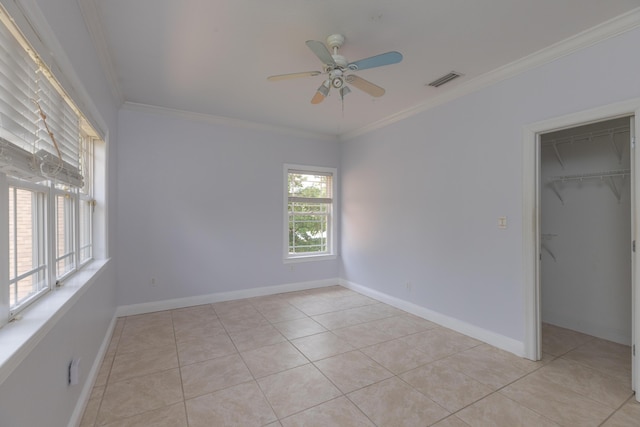 unfurnished bedroom featuring ornamental molding, ceiling fan, light tile patterned floors, a spacious closet, and a closet