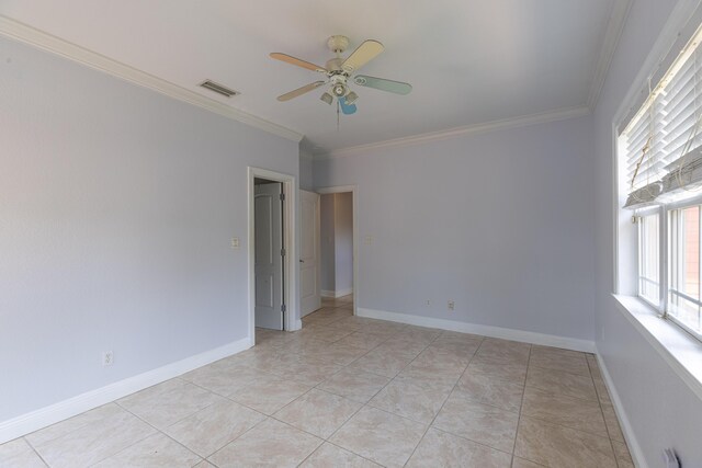 tiled empty room with ceiling fan and crown molding