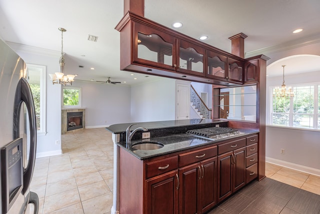 kitchen with pendant lighting, ceiling fan with notable chandelier, sink, ornamental molding, and stainless steel refrigerator