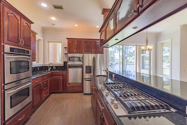 kitchen with a chandelier, decorative backsplash, stainless steel appliances, and dark stone countertops