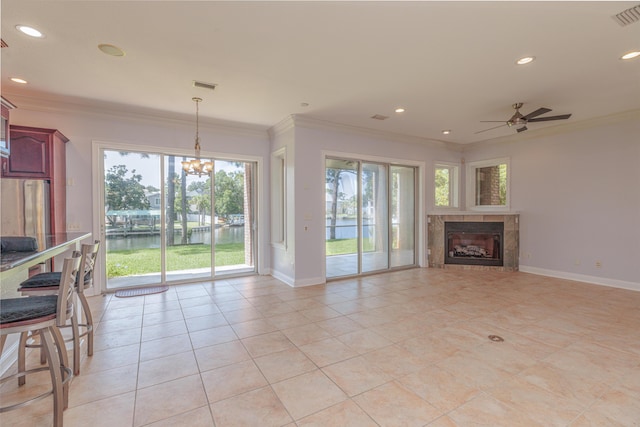 unfurnished living room with a tile fireplace, a wealth of natural light, crown molding, and a water view