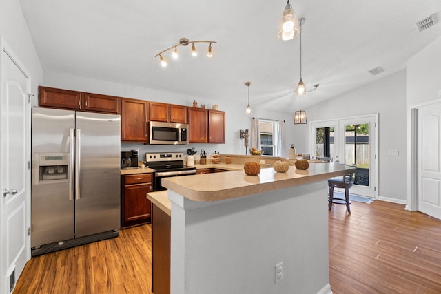 kitchen featuring french doors, stainless steel appliances, light hardwood / wood-style floors, vaulted ceiling, and decorative light fixtures