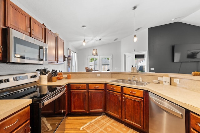 kitchen featuring stainless steel appliances, sink, light hardwood / wood-style floors, hanging light fixtures, and vaulted ceiling