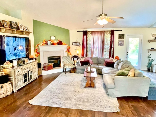 living room with ceiling fan, dark hardwood / wood-style floors, and a tiled fireplace