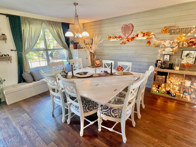 dining space with wooden walls, an inviting chandelier, and dark hardwood / wood-style flooring