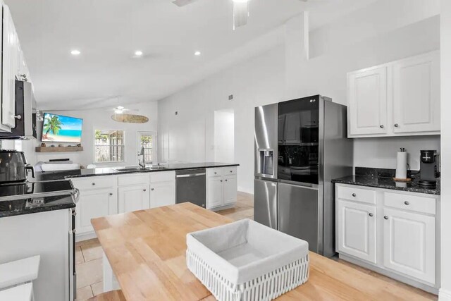 kitchen featuring lofted ceiling, kitchen peninsula, light hardwood / wood-style flooring, white cabinetry, and stainless steel appliances