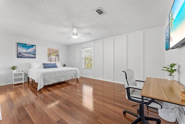 bedroom featuring hardwood / wood-style flooring, ceiling fan, and a textured ceiling