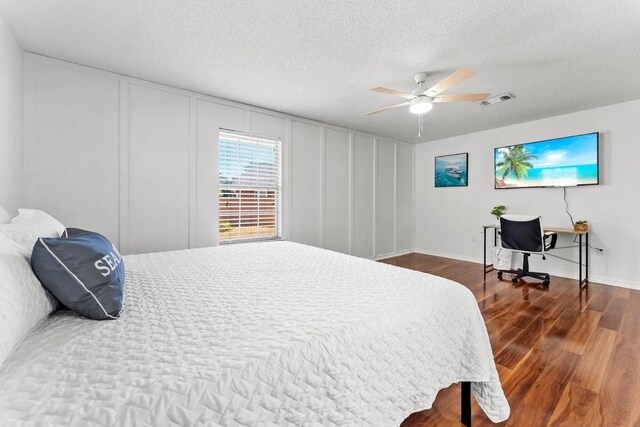 bedroom with ceiling fan, a textured ceiling, and dark hardwood / wood-style floors